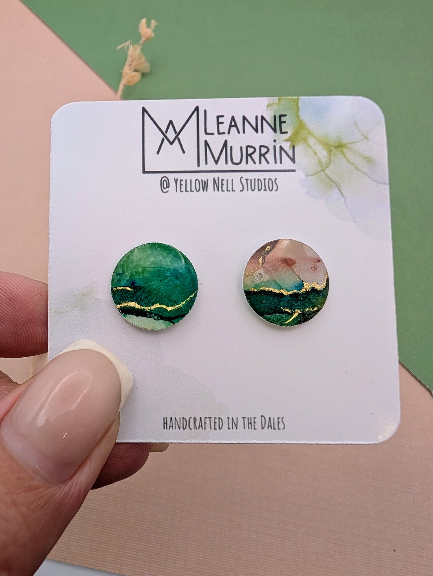 Pair of round earrings on a Leanne Murrin branded card held by a hand.