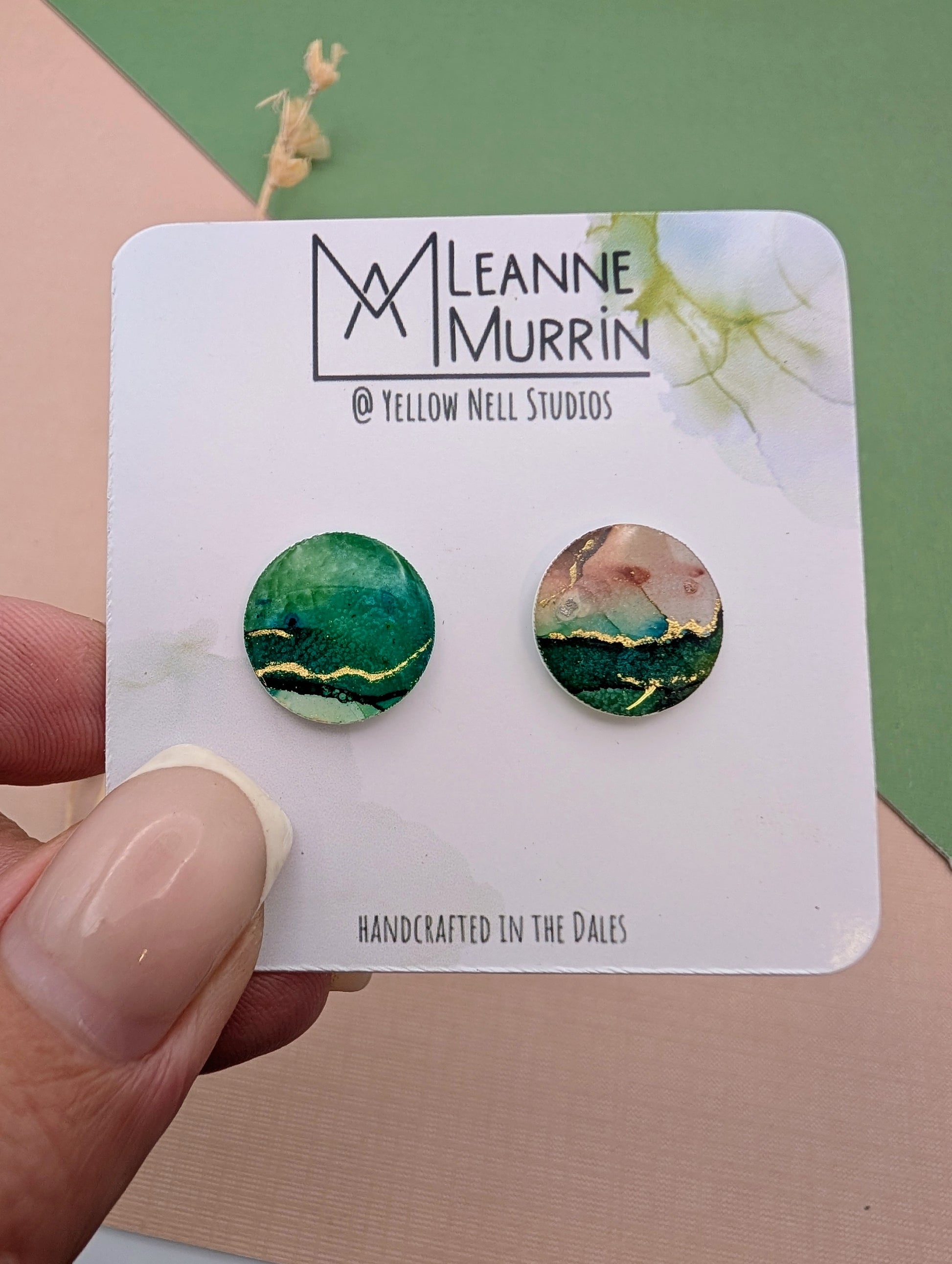 Pair of round earrings on a Leanne Murrin branded card held by a hand.