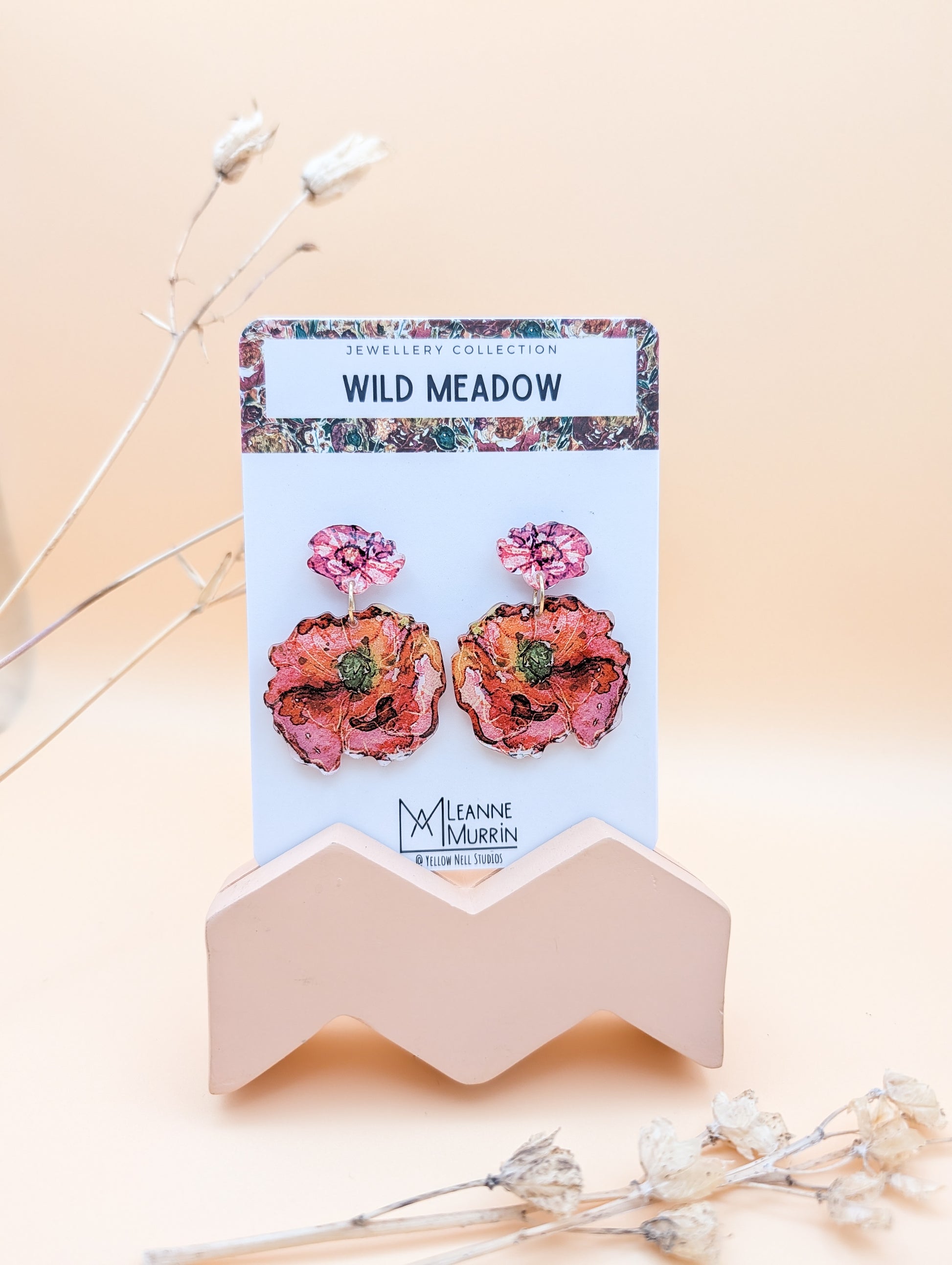Floral earrings on a branded card with a beige background